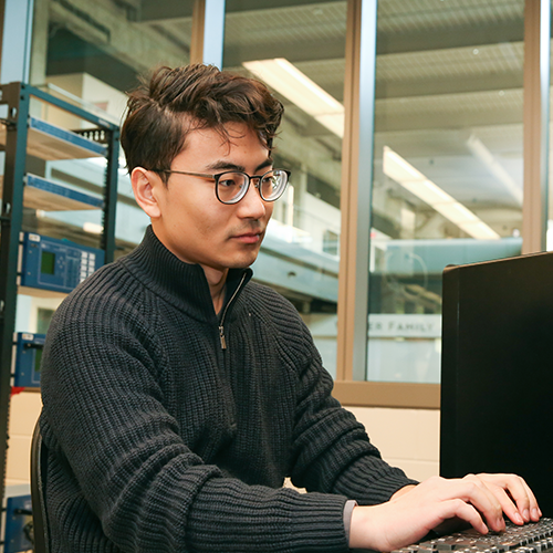 Person typing in a computer in a lab setting.