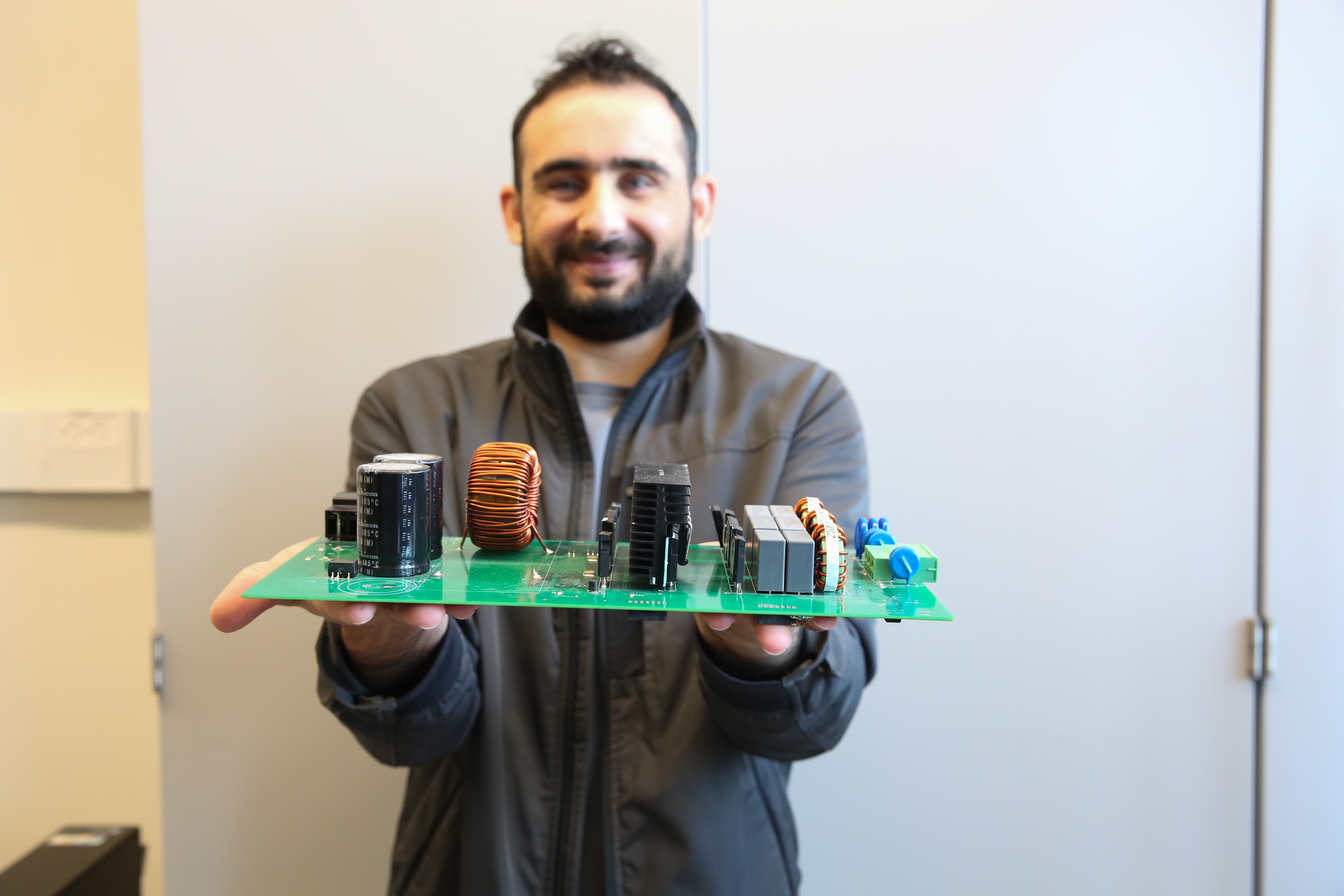 Person holding a circuit board with various electronic components.