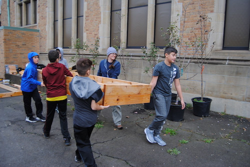 6 young students carrying a raised wood planter