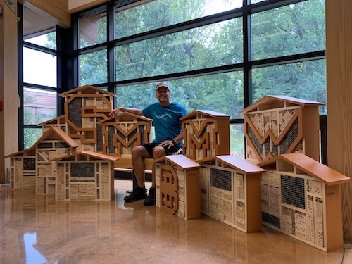 Man sits among newly created wood insect hotels.