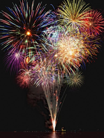 Fireworks being shot off from in the middle of water, Several bursts of colors, red, yellow, white, mixed.