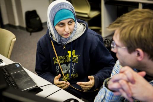 Female student wearing UM-Dearborn sweatshirt talks with male student